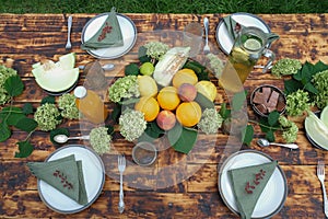 Summer table set. Outdoor dining. Table decorated fresh flowers and fruits.