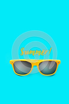 Summer! text and yellow sunglasses in intense cyan blue background. Minimal image concept for ready for summer