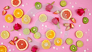 Summer theme background with fruit, citrus and flowers on pink backdrop.