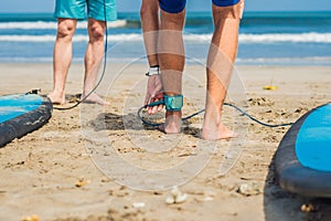 Summer time and active rest concept. Young surfer man beginner fastens leash across leg, going to surf on big barral