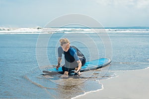 Summer time and active rest concept. Young surfer woman beginner fastens leash across leg, going to surf on big barral