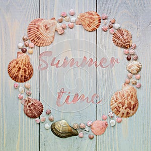 Summer time background with sea shells and lettering on blue wooden planks.
