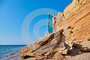 Summer time, beach day, holiday trip, surfing idea, copy space. Woman on cliff sunbathing, hot summer day on coastline.