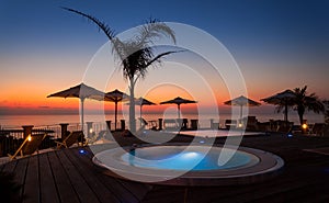 Summer time: beautiful dawn at pool area with palm and parasols, Tropea, Italy