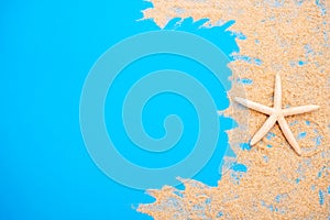 Summer time concept with sea shells and starfish on a blue wooden background and sand