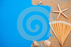 Summer time concept with sea shells and starfish on a blue wooden background and sand