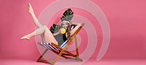 Summer time girl sitting in beach chair  on pink background with copy space