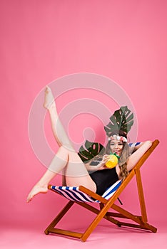 Summer time girl sitting in beach chair  on pink background with copy space