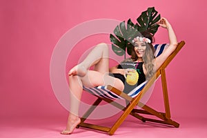 Summer time girl sitting in beach chair  on pink background with copy space