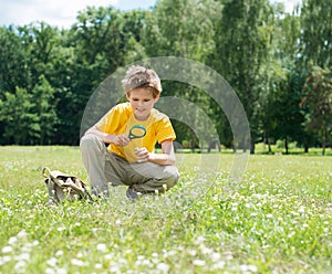 Summer time. Happy boy with magnifying glass outdoors.