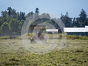 Summer time scene of a farmer working his field on an old tractor