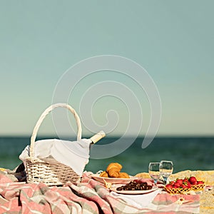 Summer time at the sea. Romantic picnic on the beach - wine, strawberries and sweets.