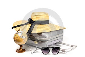 Summer time. Travel accessories with suitcase, straw hat, toy airplane and globe in minimal trip vacation concept isolated on