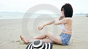 Summer time woman bikini use sunscreen lotion spf sunblock on the beach. Cheerful woman wear white bikini, short pant, straw hats