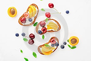 Summer toast snack bread, apricots, blueberries, cherries, basil leaves, curd cheese, sour cream, honey. Toasts