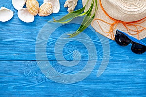 Summer travaling to the sea with straw hat, sun glasses, shells on blue background top view mock up