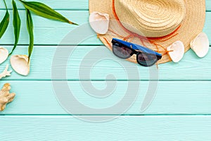 Summer travaling to the sea with straw hat, sun glasses, shells on mint green wooden background top view mock up