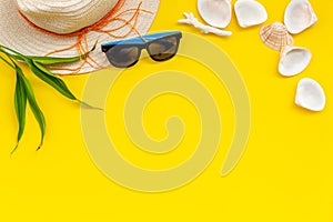 Summer travaling to the sea with straw hat, sun glasses, shells on yellow background top view mock up