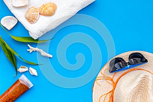 Summer travaling to the sea with straw hat, sun glasses, sunblock lotion on blue background top view mock up