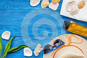 Summer travaling to the sea with straw hat, sun glasses, sunblock lotion on blue wooden background top view mock up