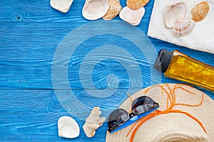 Summer travaling to the sea with straw hat, sun glasses, sunblock lotion on blue wooden background top view mock up