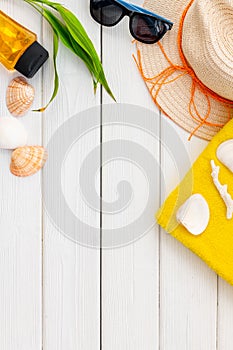 Summer travaling to the sea with straw hat, sun glasses, sunblock lotion on white wooden background top view mock up