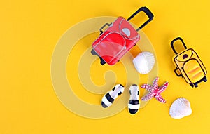 Summer travel background. Miniature traveler accesories on yellow background with bags, moccasins, seashells and starfish.