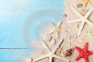 Summer travel background from seashell, starfish and sand on blue table top view.