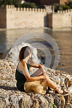 Summer travel concept. Female sitting on the rocks