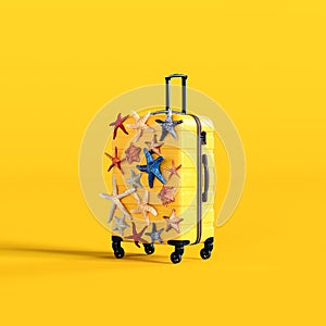 Summer travel concept. Yellow luggage covered with colorful starfish on yellow background.