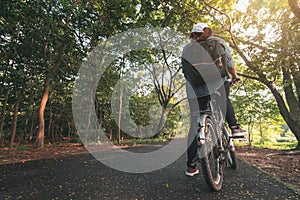 Summer travel concept, Young asian woman wear jean shirt riding bicycle on forest trail at morning tropical in her vacation