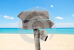 summer travel destinations options. Direction road sign with wooden arrows on beach and sea