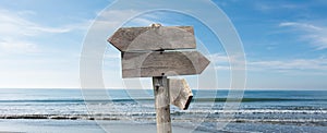 Summer travel destinations options.  Direction road sign with wooden arrows on beach and sea