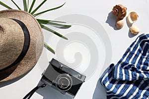 Summer travel vacation background with sun hat, camera, sea shells, tropical palm leaf on white background. Flat lay composition