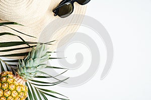 Summer travel vacation concept. Top view female straw beach hat, sunglasses, pineapple, palm leaf on white background