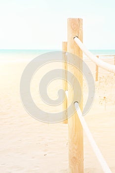 Summer travel vacation concept. White pinkish beach sand turquoise ocean blue sky. Tranquil idyllic scene. Rope railing