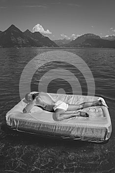 Summer Travel vacation holiday. Man rest at the lake, enjoy summer holiday. Muscular man lying on cozy Mattresses, sleep