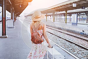 Summer travel, woman with suitcase waiting for her train