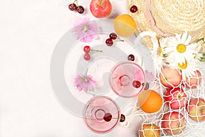 Summer trendy banner on bright background.Straw hat,fruits in eco bag,refreshing alcoholic drinks and chamomile flowers on sunny