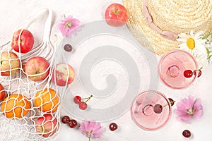 Summer trendy banner on bright background.Straw hat,fruits in eco bag,refreshing alcoholic drinks and chamomile flowers on sunny