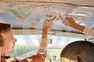 Summer trip concept. cropped friends or couple looking at map to plan a camper van trip