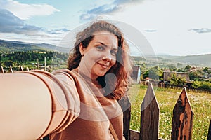 Summer trip to the mountains. A young woman takes a selfie on top of a mountain in the evening at sunset.