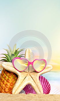 Summer tropical sea with pineapple, starfish and sunglasses on hot sand beach. Travel and vacation concept with copy