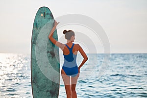 Summer vacation and adventure idea. Sunny weather on beach, woman with surfboard. Calm sea, sandy coastline. Copy space