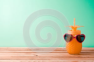 Summer vacation background with cute pineapple juice and sunglasses on wooden table