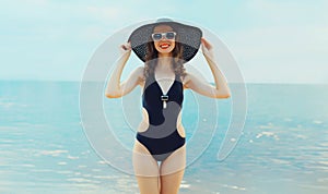 Summer vacation, beautiful happy smiling woman in bikini swimsuit and straw hat on the beach on sea coast background