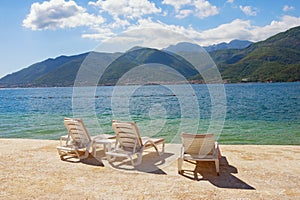 Summer vacation. Beautiful sunny landscape with chaise lounges on beach. Montenegro, Adriatic Sea, view of Bay of Kotor