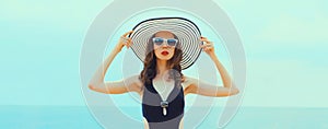 Summer vacation, beautiful young woman in bikini swimsuit and straw hat on the beach at sea