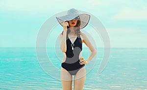 Summer vacation, beautiful young woman in bikini swimsuit and straw hat on the beach on sea coast background