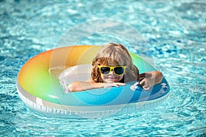 Summer vacation. Boy relaxing on the inflatable ring in pool. Summertime kids weekend. Funny boy on rubber circle at